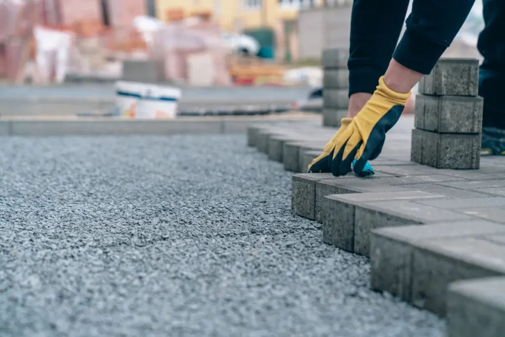 A worker laying some pavers for a landscaped commercial property